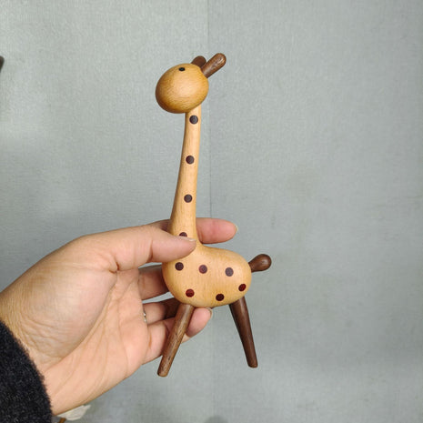 Giraffenfigur aus Holz mit braunen Punkten, in der Hand gehalten