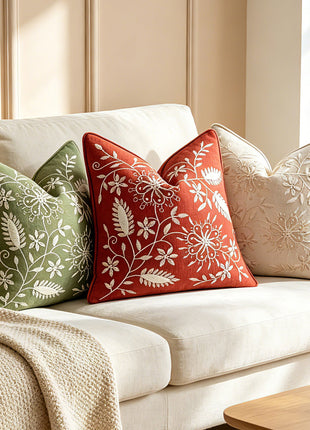 Green, brown and ivory botanical pillow covers on a sofa