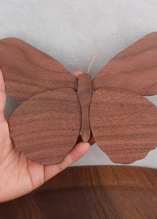 Schmetterlingsdeko aus Massivholz in brauner Holzoptik, von einer Hand gehalten