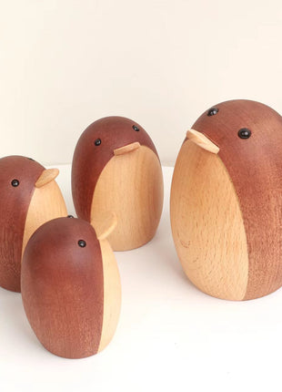 Vier Holzfigur-Pinguine, braun und hell, verschiedene Größen, nebeneinander stehend