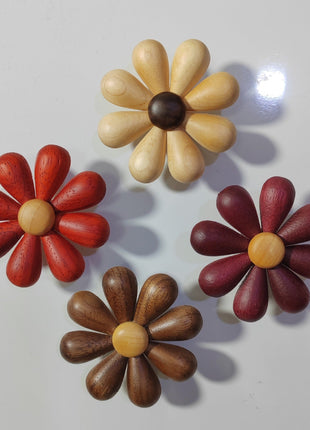 Set aus vier Holzblumen mit roten, dunklen und hellen Blütenblättern auf Stab und Sockel