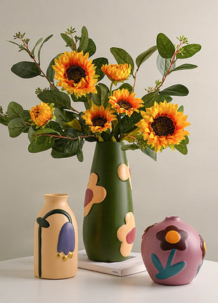 Grüne handbemalte Keramikvase mit Sonnenblumen, dazu cremefarbene Vase und rosafarbene Kugelvase