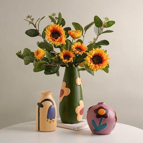 Grüne handbemalte Keramikvase mit Sonnenblumen, dazu cremefarbene Vase und rosafarbene Kugelvase