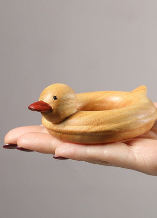 Enten-Holzskulptur im Schwimmring aus hellem Sandelholz, roter Schnabel, in Händen gehalten
