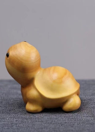 Lächelnde Schildkröten-Holzfigur aus hellgelbem Holz, seitlich aufliegend.
