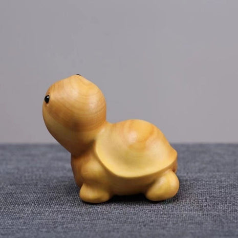 Lächelnde Schildkröten-Holzfigur aus hellgelbem Holz, seitlich aufliegend.