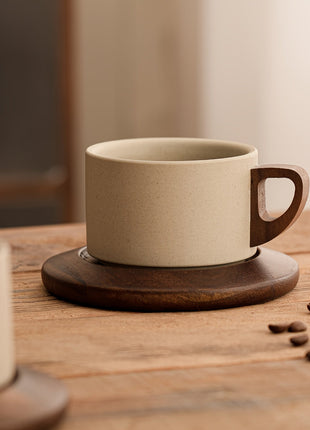 Keramik-Tasse mit Untertasse, beiger Becher mit braunem Griff und ganzen Kaffeebohnen
