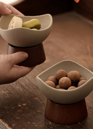 Zweiteilige Dessertschale aus Keramik: obere Schale creme, brauner Fuß, gefüllt mit Snacks