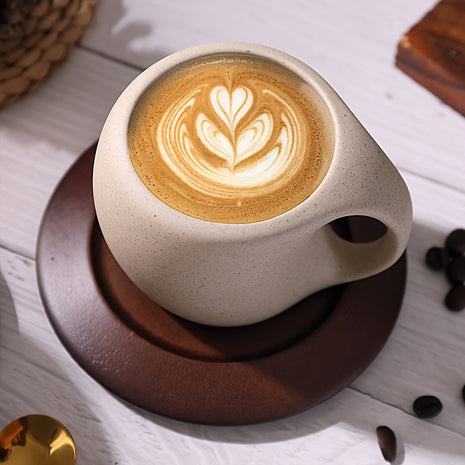 Steingut-Kaffeetasse, hellbeige mit Espressocrema, auf braunem Holzuntersetzer