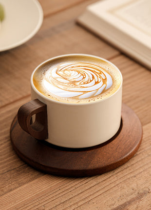 Cremefarbene Keramiktasse auf brauner Untertasse mit Latte-Art im Kaffee