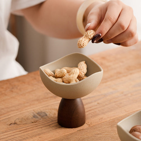 Cremefarbene Keramik-Dessertschale auf Walnussholz-Sockel, mit Gebäck gefüllt