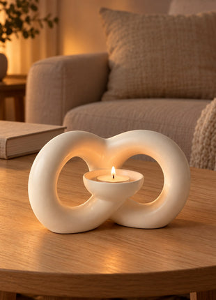 Ivory infinity-shaped ceramic tealight holder on an oak coffee table in a warm neutral living room